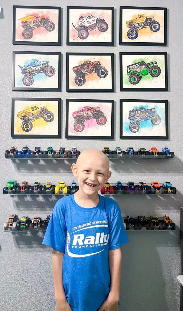 Wilder smiling in front of his wall of monster truck art and toy trucks