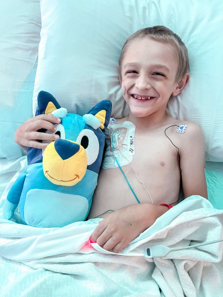 Wilder smiling in a hospital bed, hugging a stuffed toy