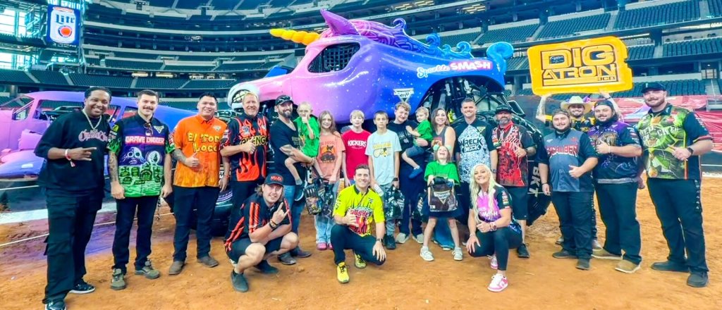 Wilder and his family with the Monster Jam drivers in front of a monster truck